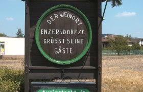 Wooden plaque in Enzersdorf an der Fischa with welcoming text and reference to the Heurigen restaurant.