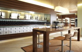 Modern tasting room with wooden table, wine glasses and wine bottles.
