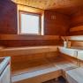 Interior view of a wooden sauna with window and sauna bucket.