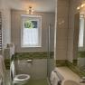 Modern bathroom with green tiles, shower, WC and washbasin.