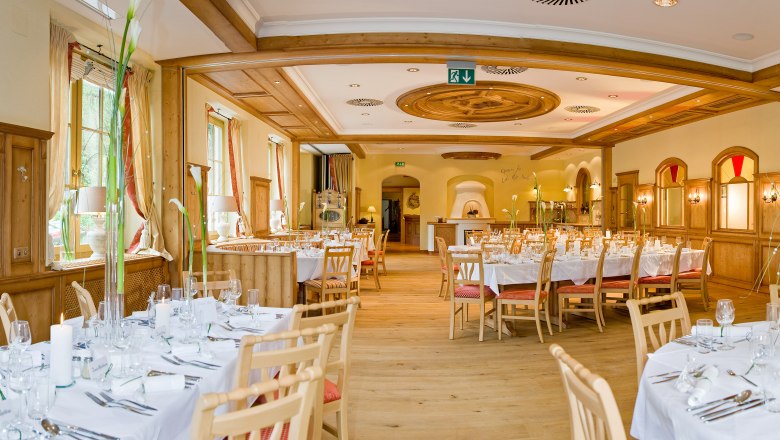 Elegant dining room with laid tables and wood paneling.