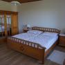 One bedroom with a wooden double bed, a closet with mirrors and two bedside tables with lamps.