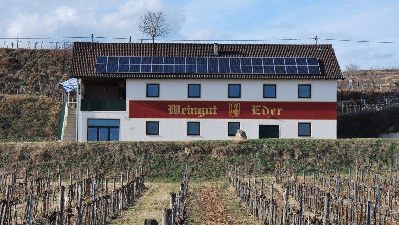 Eder winery with solar panels on the roof and vines in the foreground.