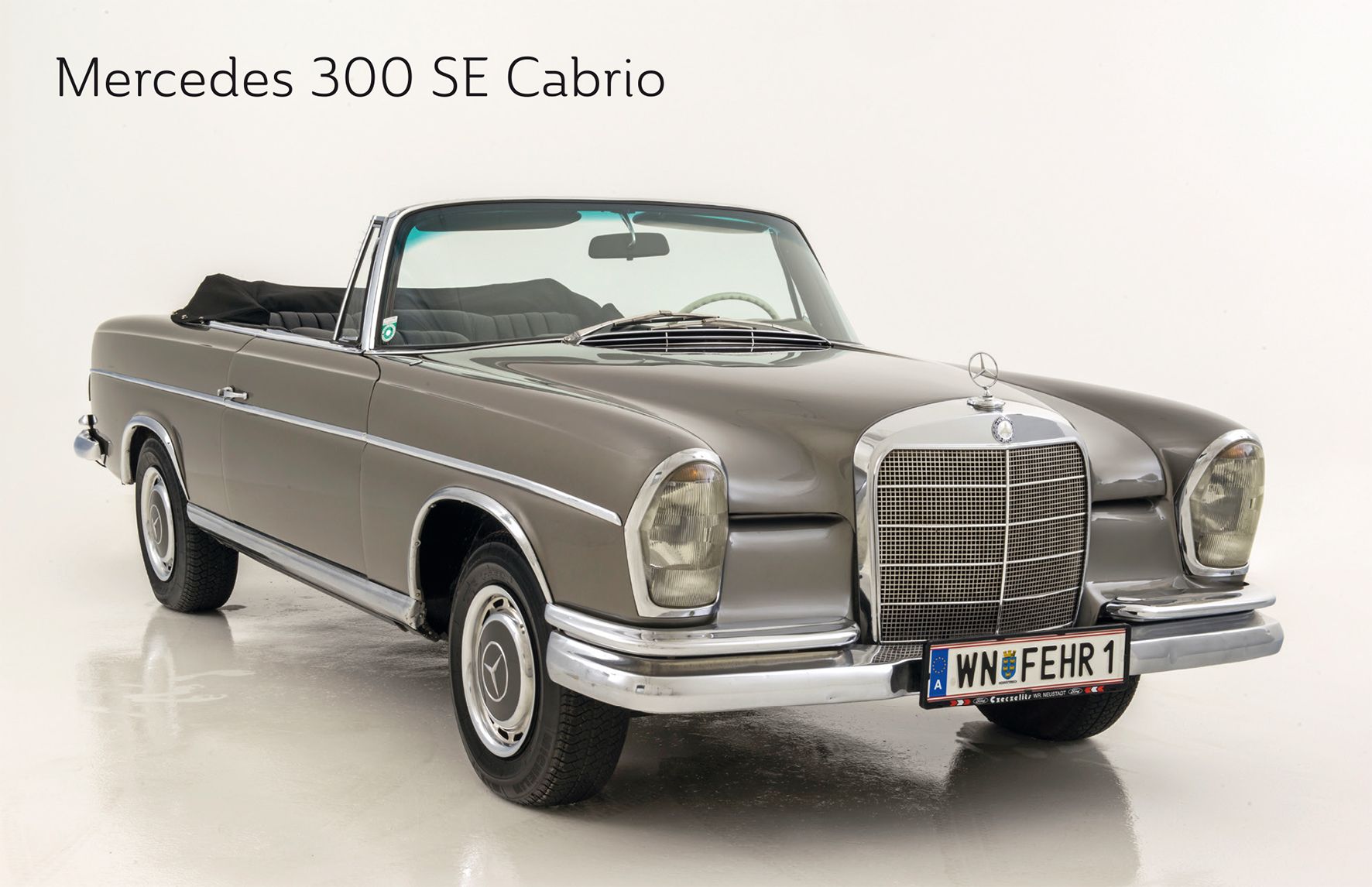 A gray Mercedes 300 SE convertible with an open top on a white background.