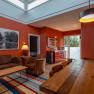 Interior view of a modern living room with red walls, wooden table, sofa and kitchenette.