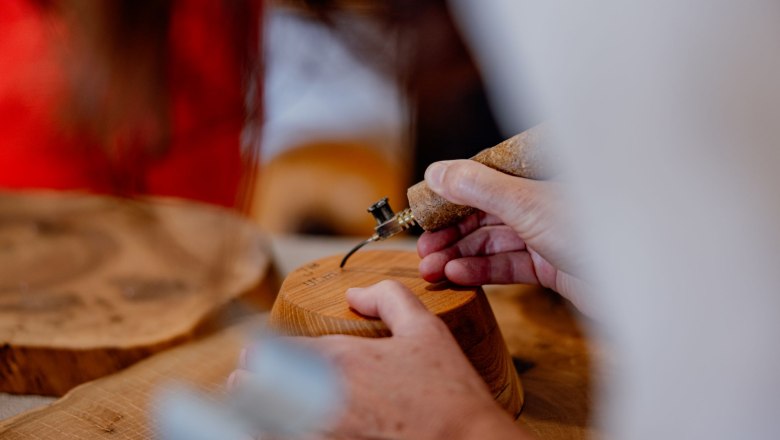 Close-up of hands working on wood with a burning tool.