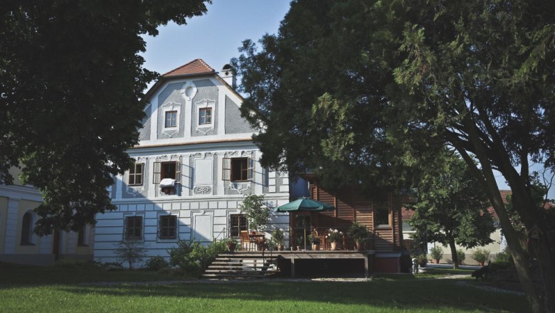 Historic building with terrace and trees in the foreground.