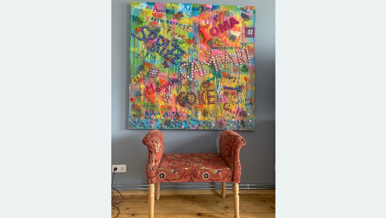 Colorful painting with lettering above a red bench.