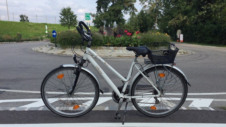 Bicycle on a road in front of a traffic circle in Tulln, surrounded by flowers and trees.
