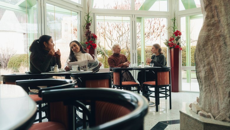 In the cozy atmosphere of Konditorei Nöbauer, guests enjoy delicious treats and stimulating conversation. The large windows offer a magnificent view of the wintry landscape of the Vienna Alps, while the warm colors of the interior create an inviting atmosphere.