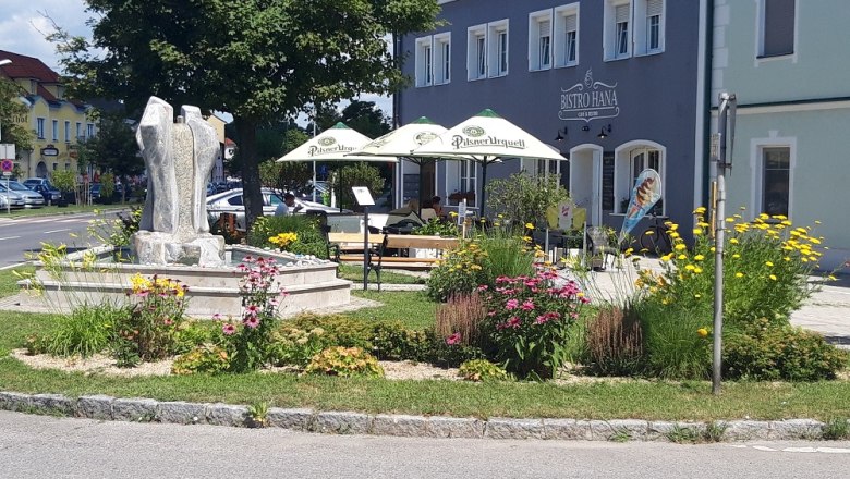 Exterior view of a café with garden and sculpture.