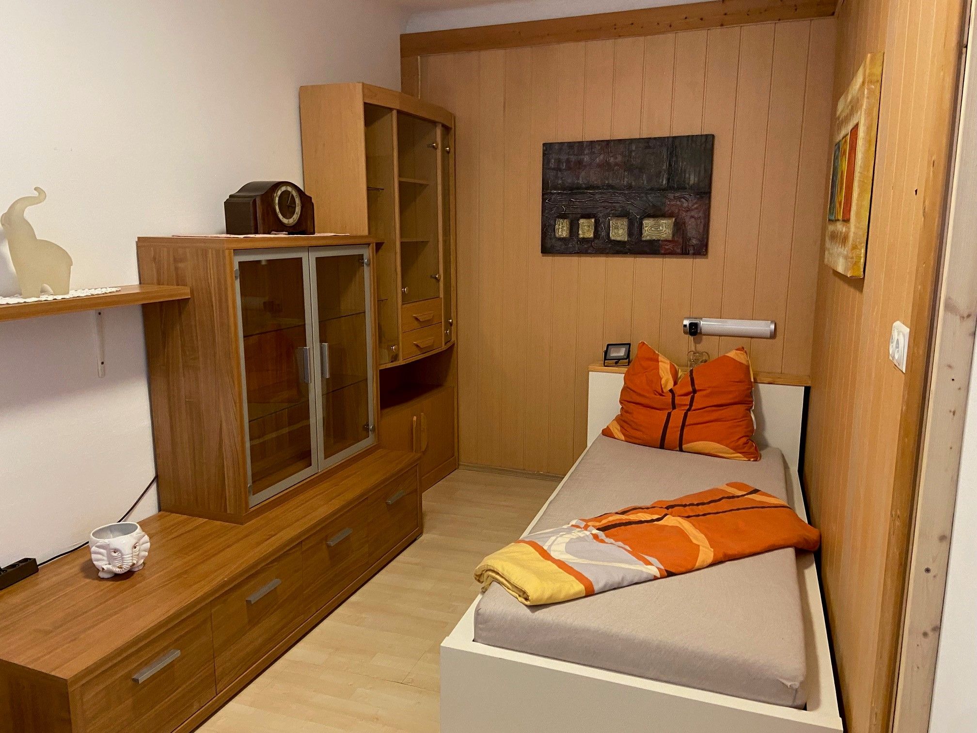 Single room with wooden furniture, single bed and decoration.