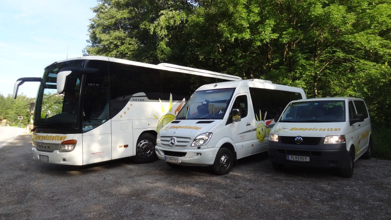 Three white vehicles with the Humpelstetter logo, parked on a gravel lot in front of trees.