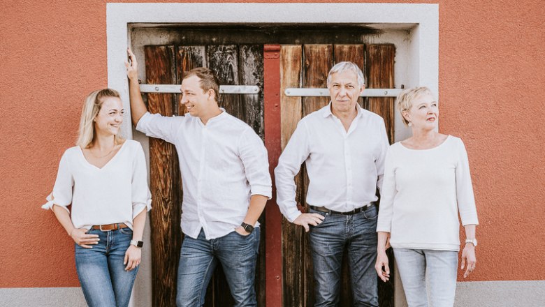 Ladentrog family, © Stefan Jurecek Four people are standing in front of a wooden door, all dressed in white.