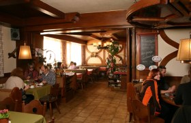 Cozy restaurant with wooden furniture and guests at tables.