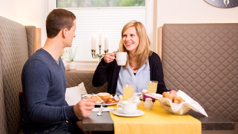 Two people having breakfast at a table with a yellow tablecloth.