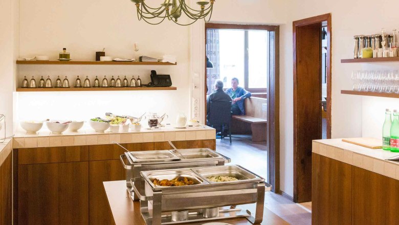 Buffet room with food and view into an adjoining room with two people.