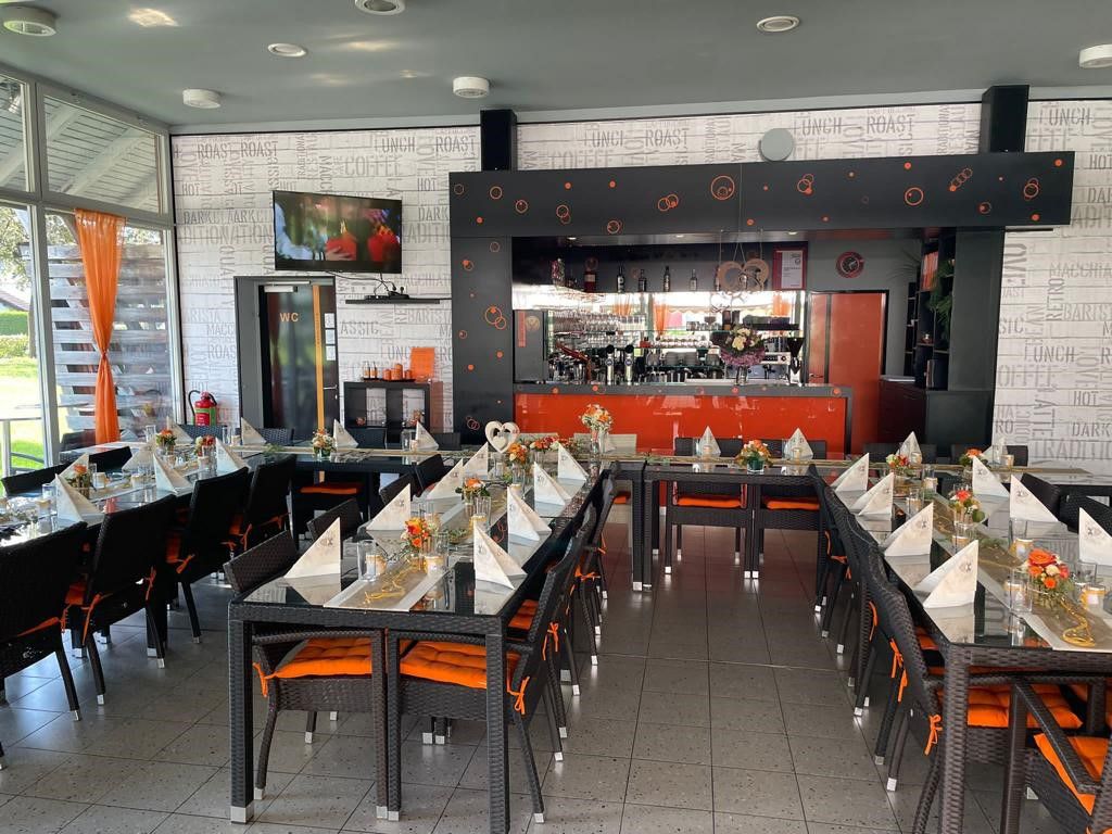 A stylishly furnished café with laid tables and a bar in the background.