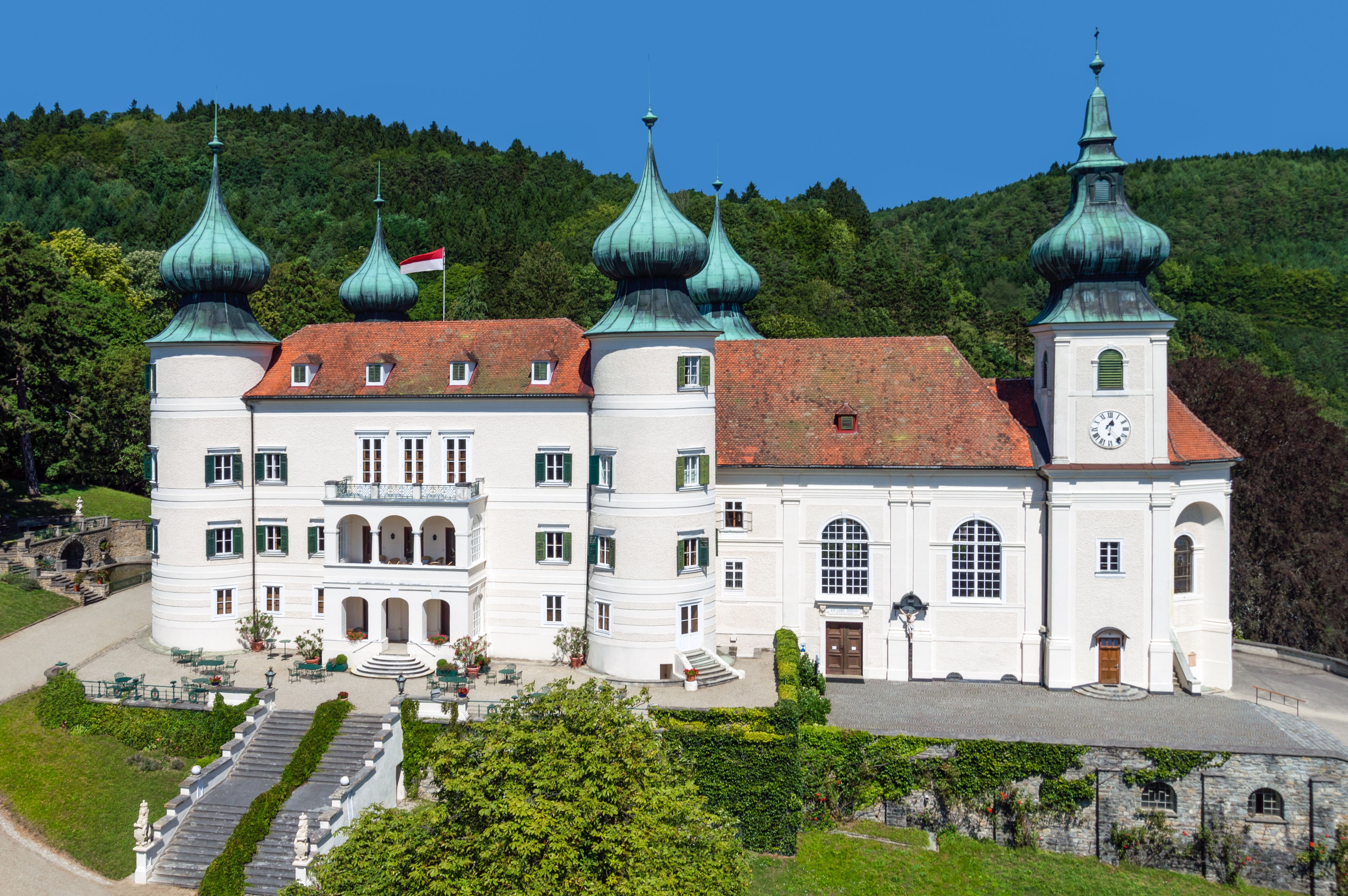 Artstetten Castle with towers and gardens against a wooded background.