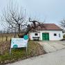 White building with green gate and sign 'freilich' in a rural setting.