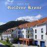 Gasthof-Hotel Goldene Krone in front of a wooded hill with a castle in the background.
