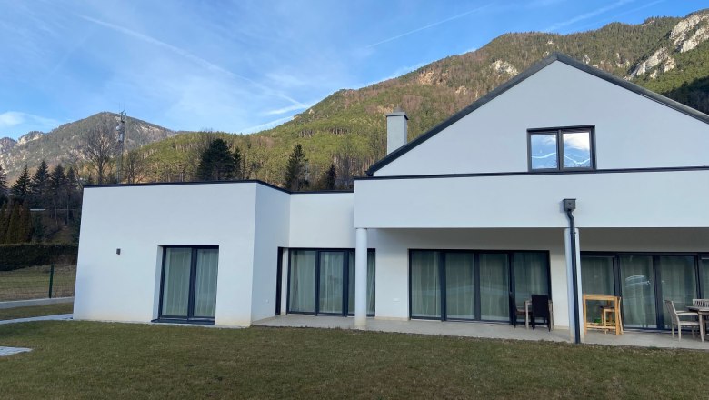 House view, © Wiener Alpen Modern white house with large windows against a mountain backdrop.