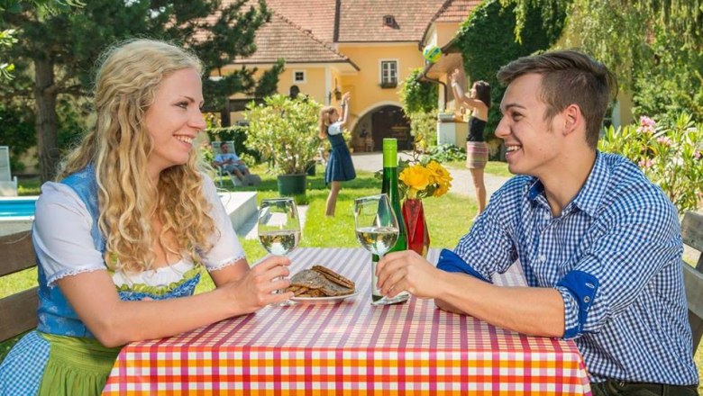 Coziness at the Winzerhof, © Winzerhof Bogner Two people are sitting at an outdoor table drinking wine.