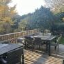 Terrace with wooden tables and chairs, surrounded by autumnal trees and plants.