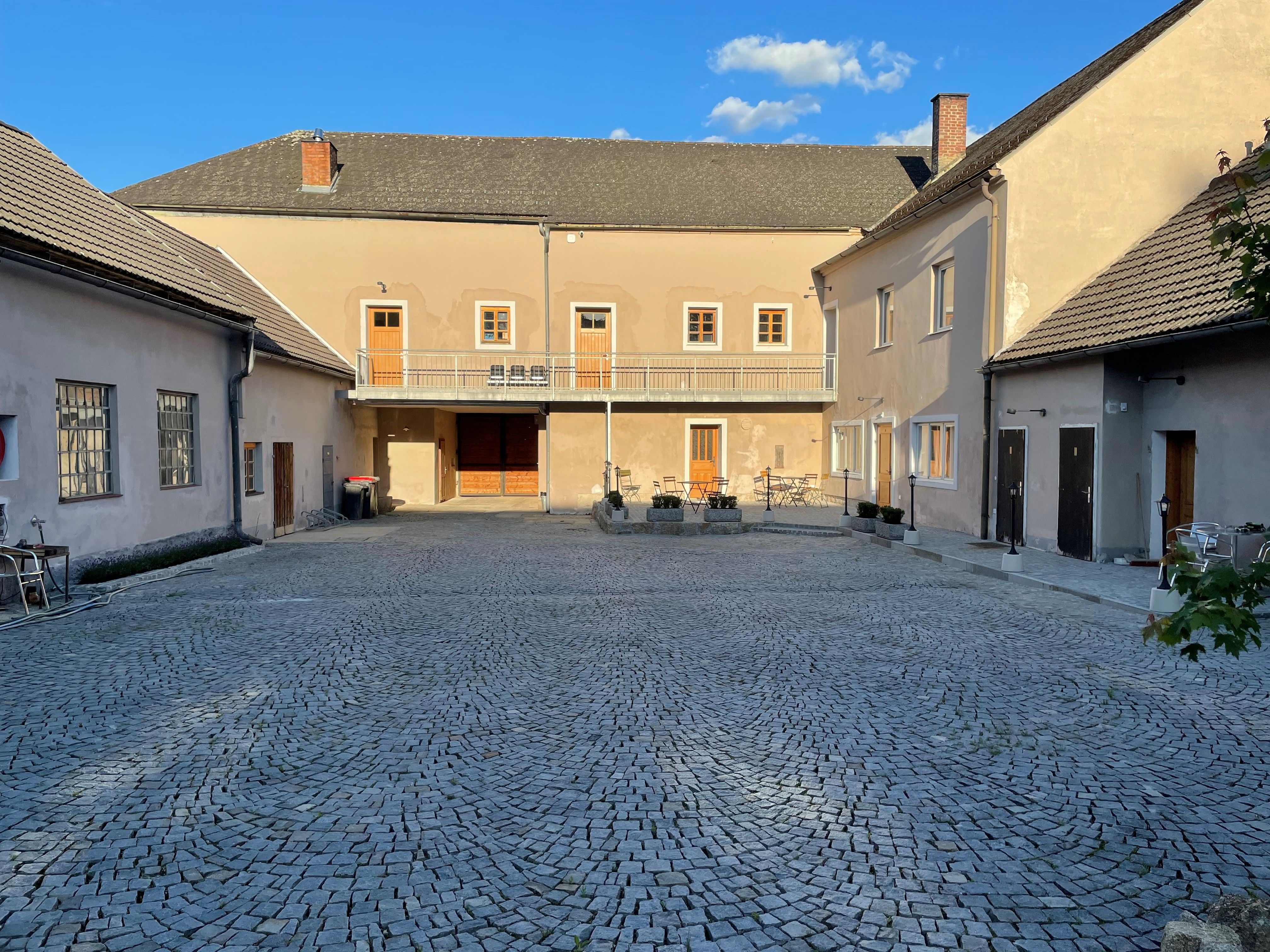 A paved courtyard with surrounding buildings and a blue sky in the background.