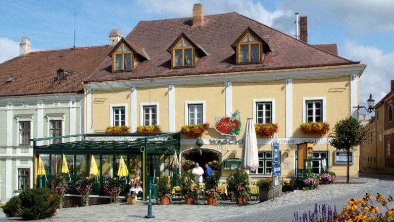 A traditional inn with a yellow fa&ccedil;ade and floral decorations.
