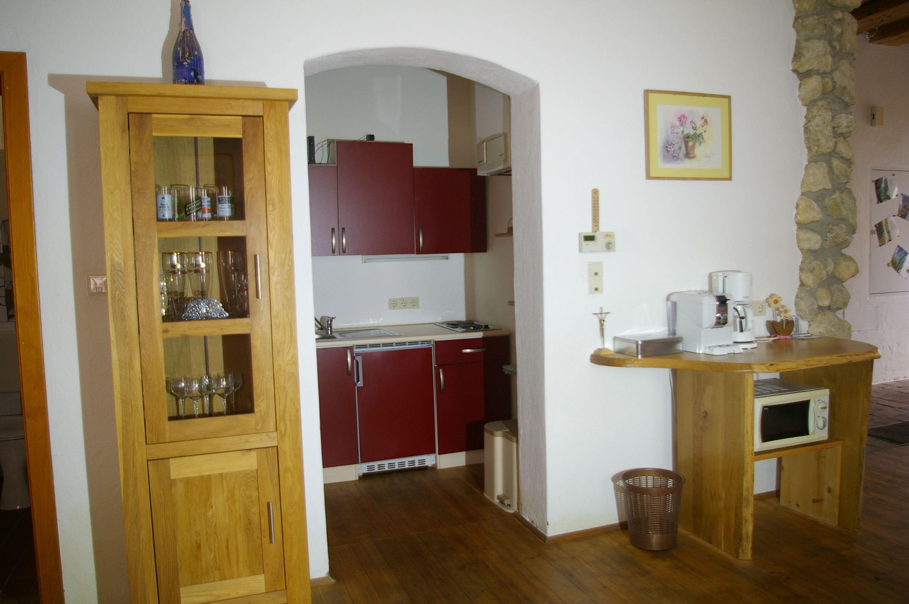 Small kitchen with wooden furniture, red cupboards and coffee machine.