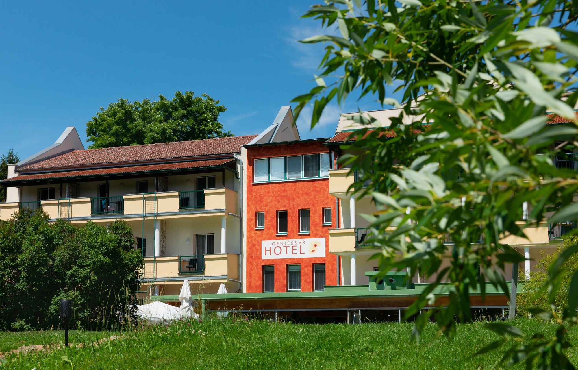 Exterior view of the Hotel-Restaurant Liebnitzmühle with green lawn and trees in the foreground.