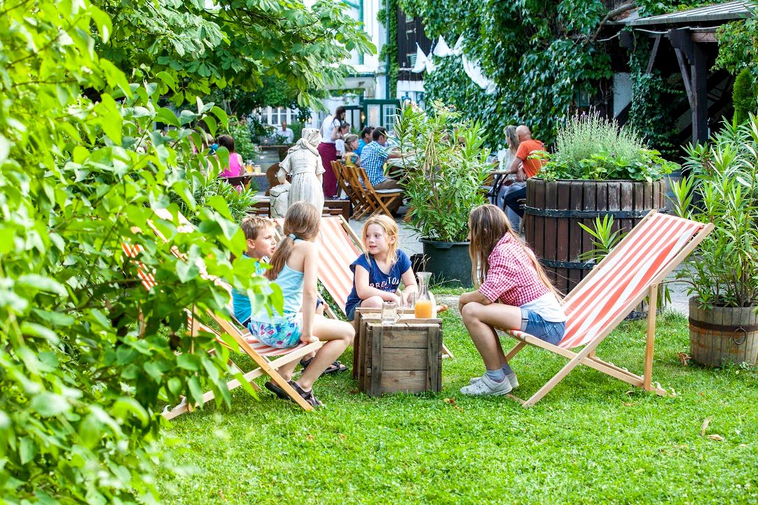 Children sit on deckchairs in the garden of a café.