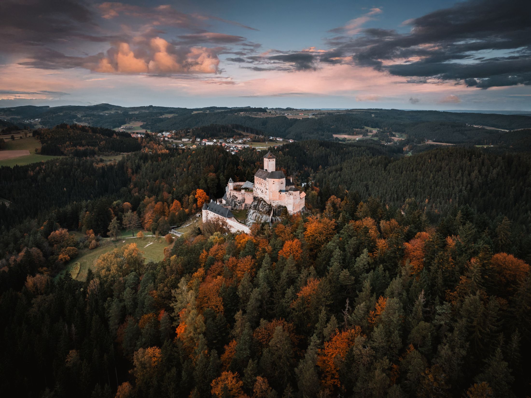 Aerial view of Rappottenstein Castle surrounded by autumnal forests.