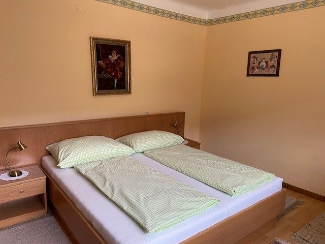 A cozy double room with a double bed, green bed linen and two pictures on the wall.