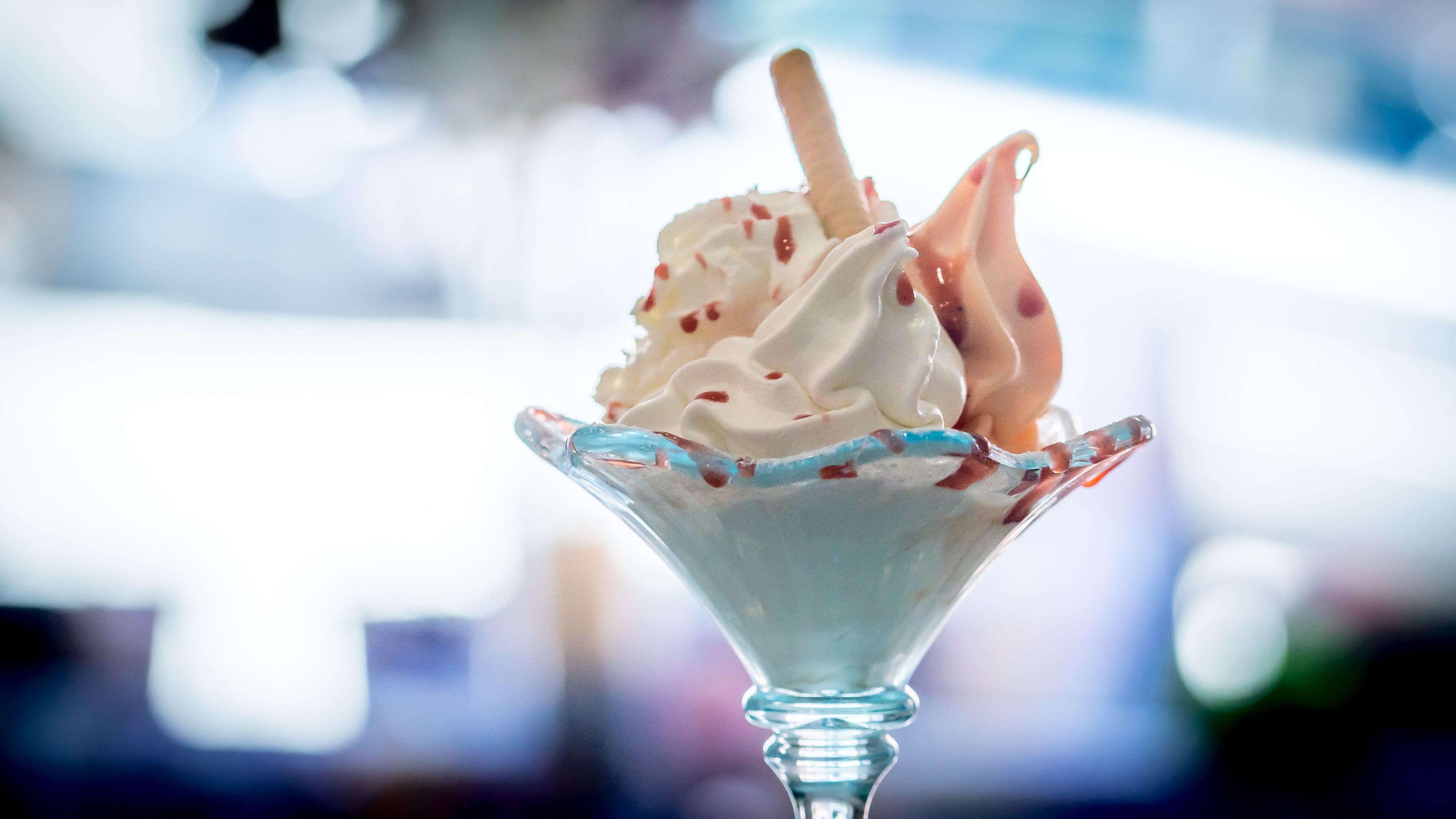A sundae with cream and sauce in a glass on a blurred background.