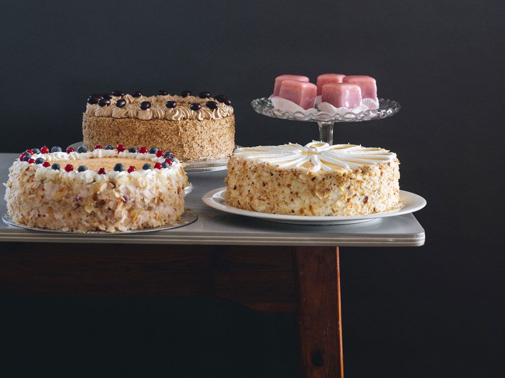 Three cakes and pink pastries on one table.
