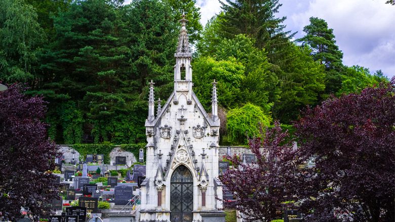 A Gothic burial chapel in a cemetery, surrounded by trees and gravestones.