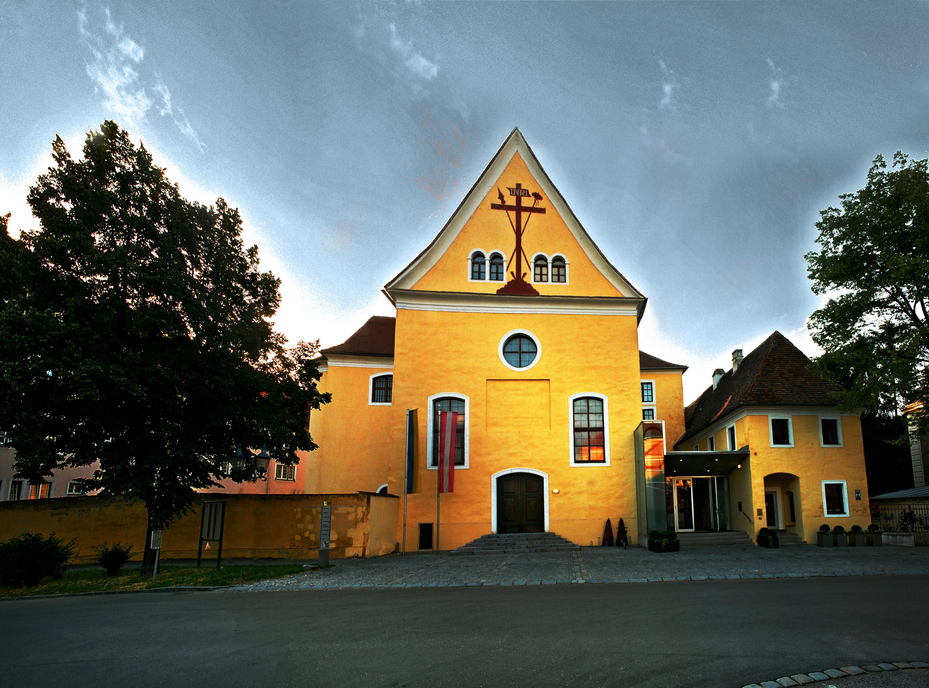 Yellow building with cross symbol and flags in front of the entrance.