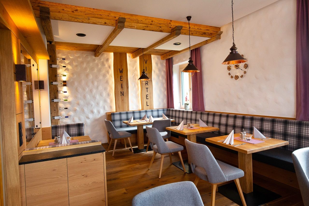 Cozy restaurant with wooden furniture, laid tables and purple curtains.