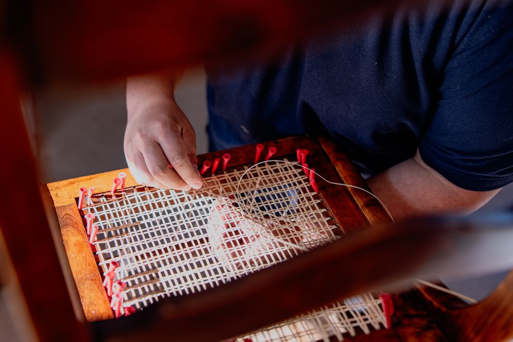 A person repairs a Thonet chair with Viennese wickerwork.