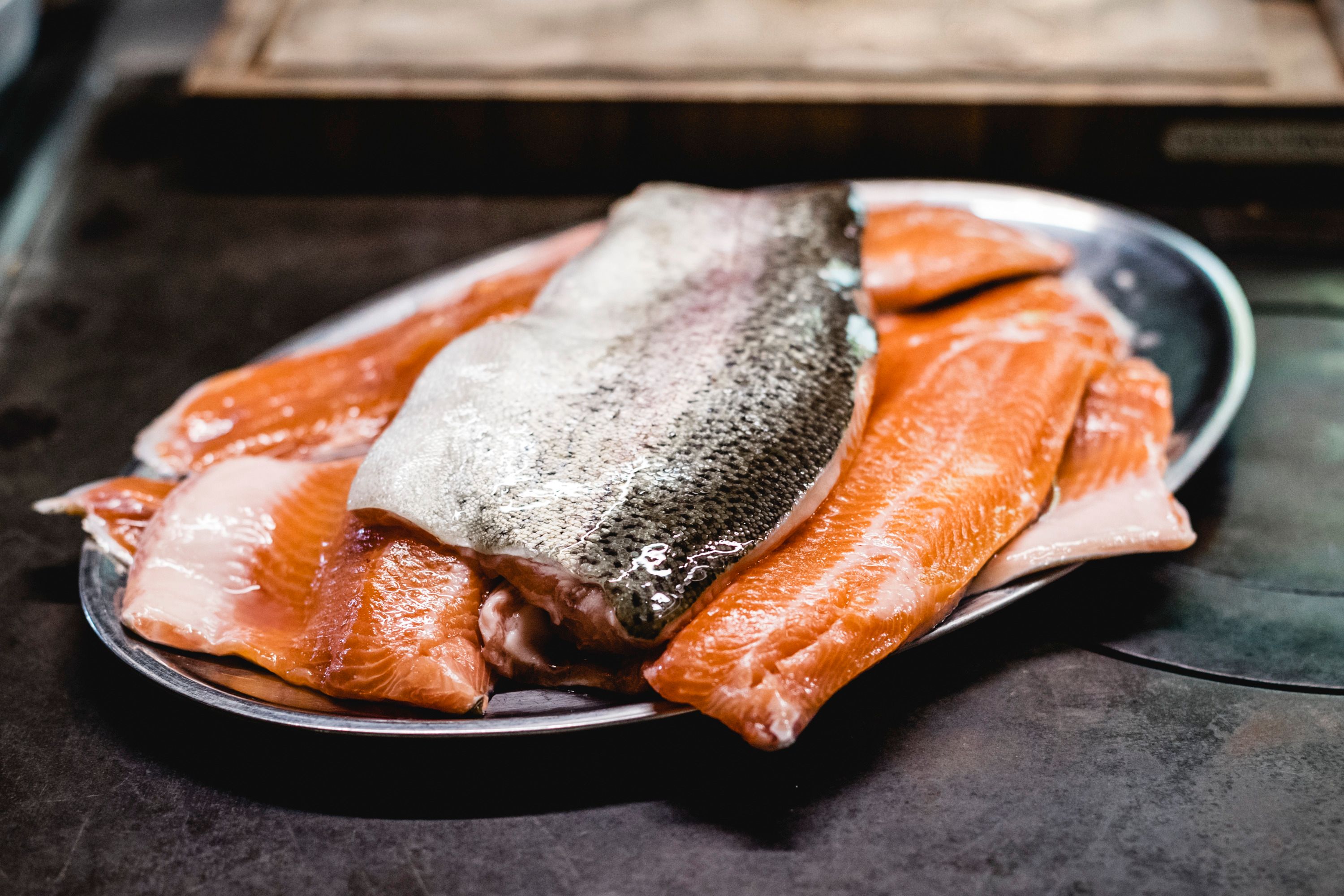 Fresh salmon fillets on a metal tray.