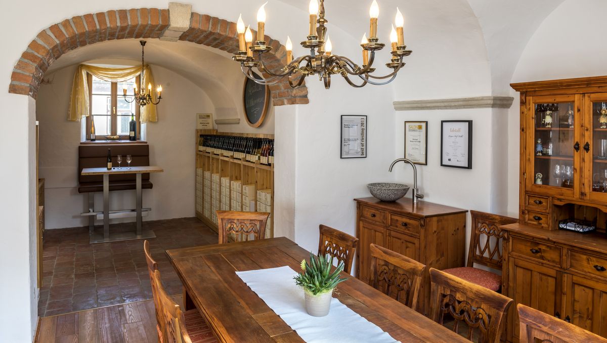 Cozy room with wooden furniture, chandelier and wine rack.