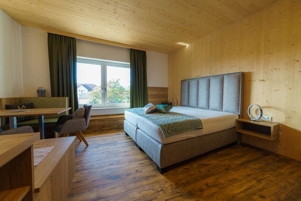Modern hotel room with double bed, wooden walls and large window.