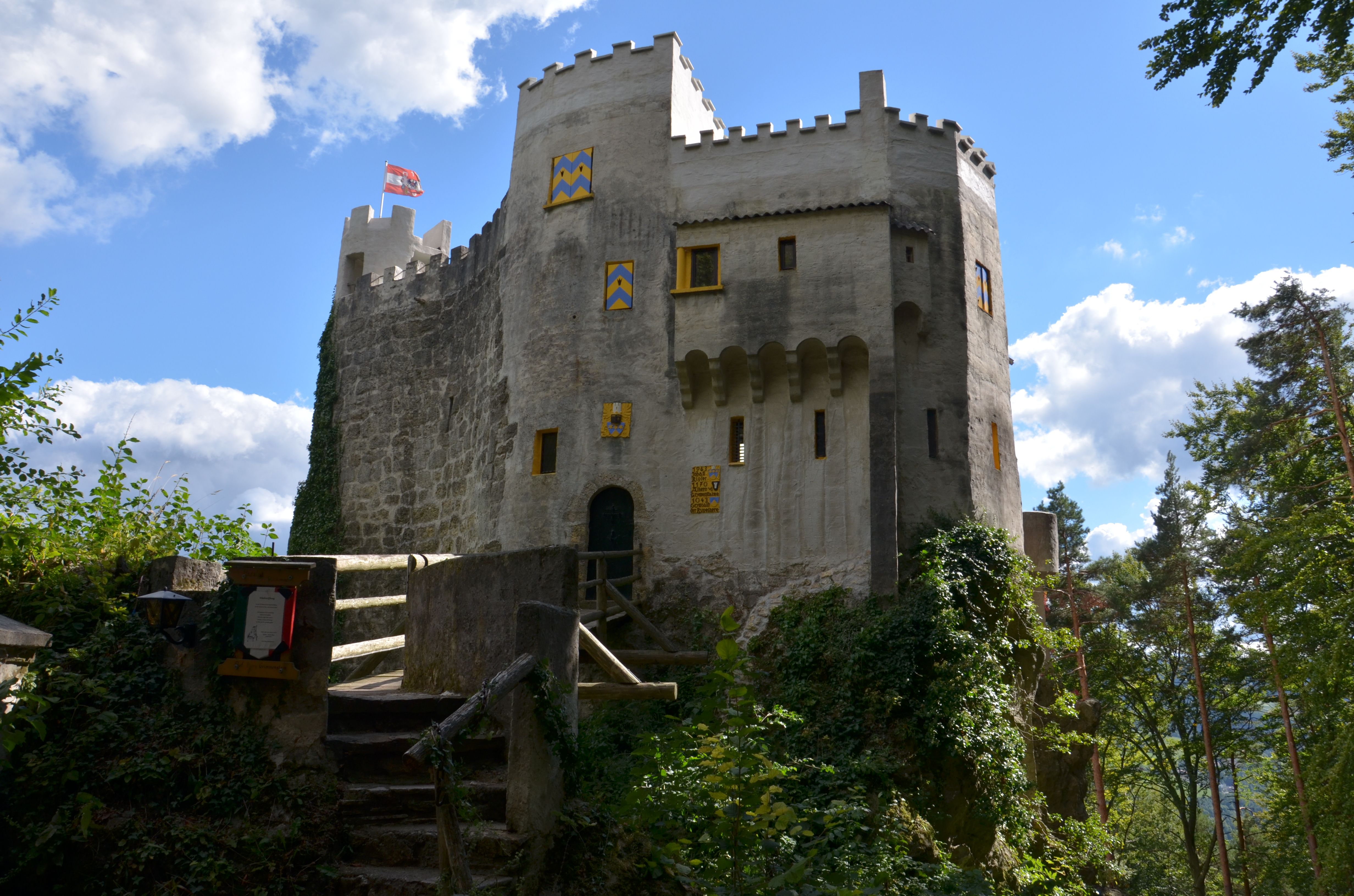 Grimmenstein Castle with bridge, battlements and blue and yellow painted shutters in the countryside.