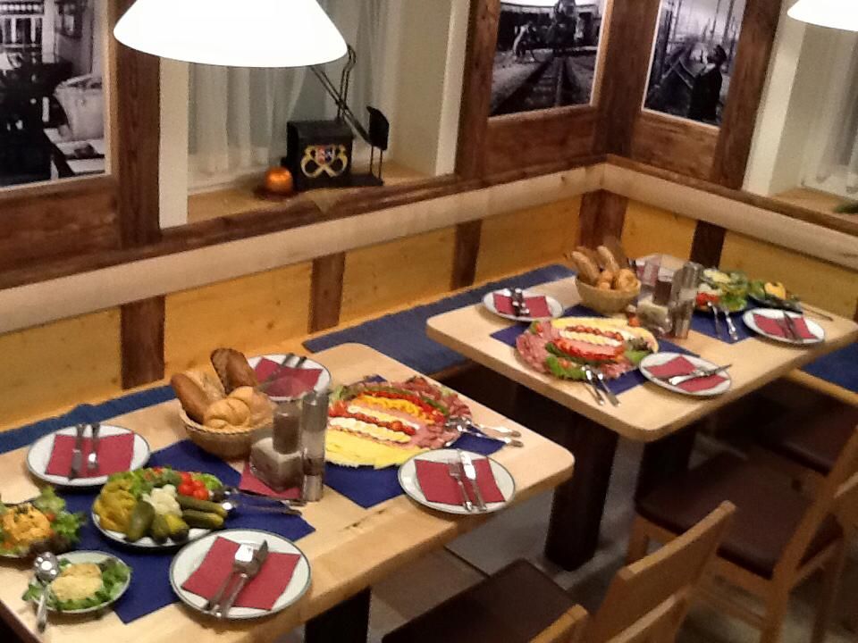 A table set in a rustic restaurant with bread, cold cuts and salads.