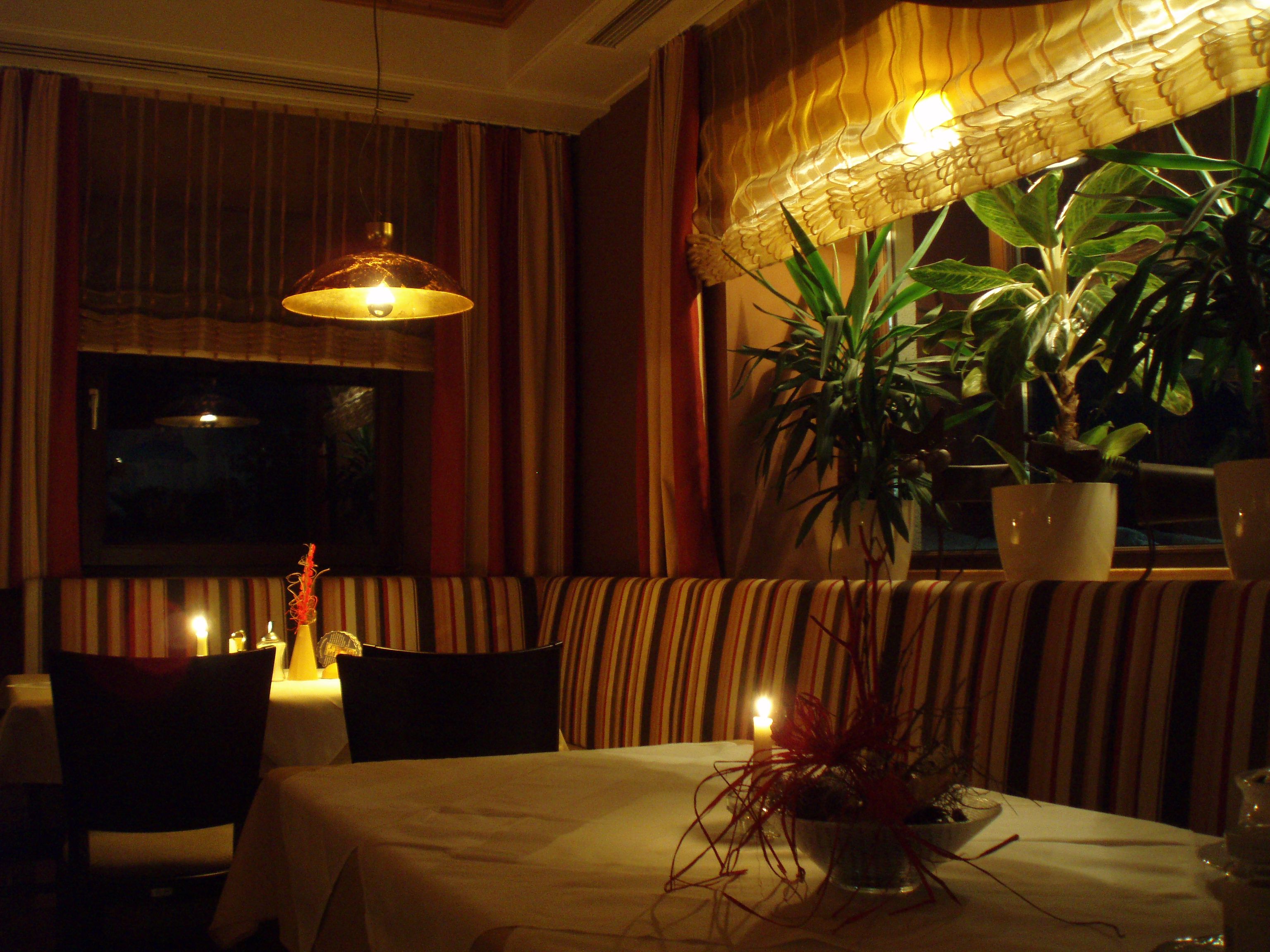 Cozy restaurant with candlelight and plants.