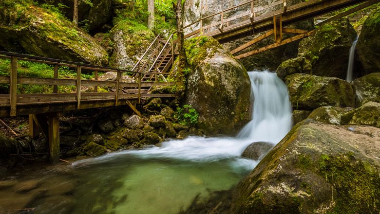Wooden bridges and waterfall in a wooded gorge.