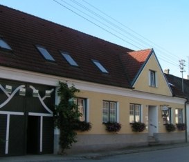 Yellow building with red roof tiles and flower boxes on the windows.