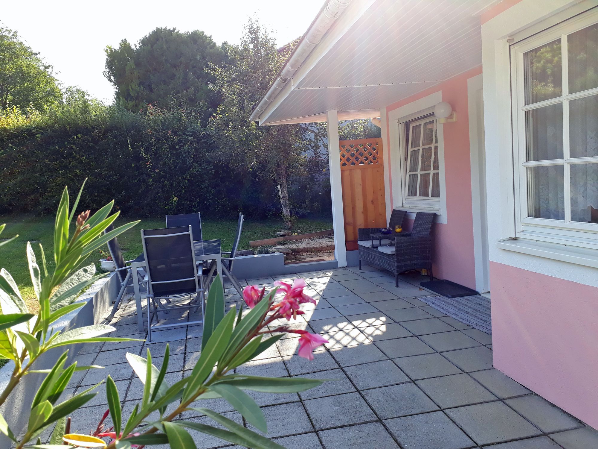 Terrace with garden furniture and pink house facade.